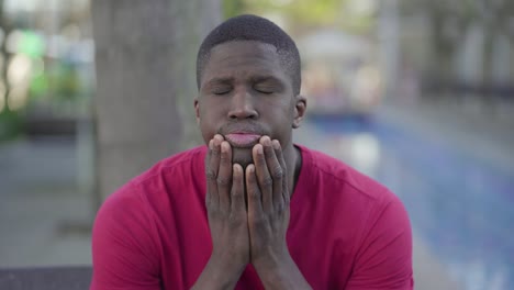 Afro-American-man-suffering-from-headache-in-park,-massaging-head